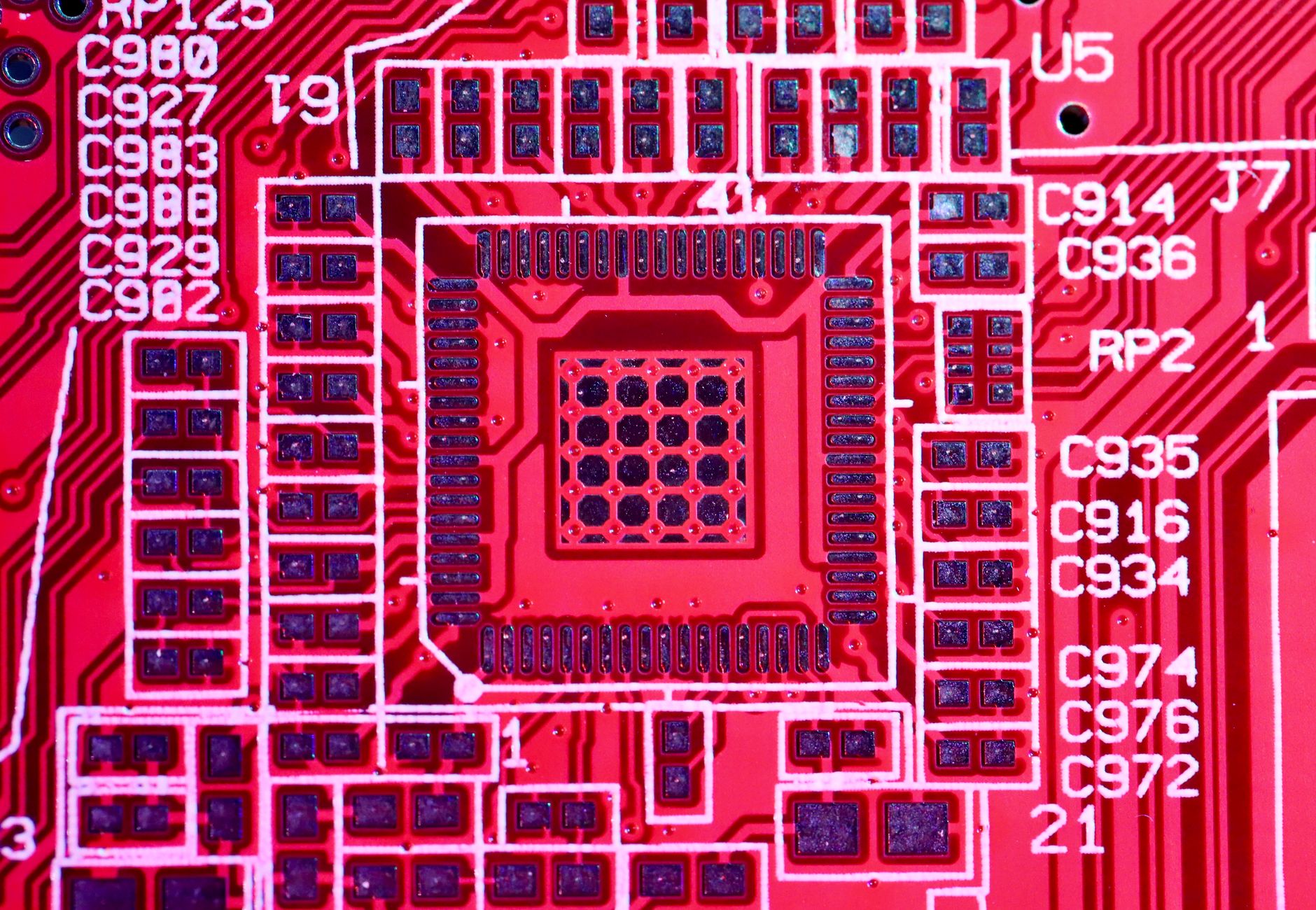 Top view of contemporary bright red printed board with electric circuits and various numbers with letters of modern electronic device
