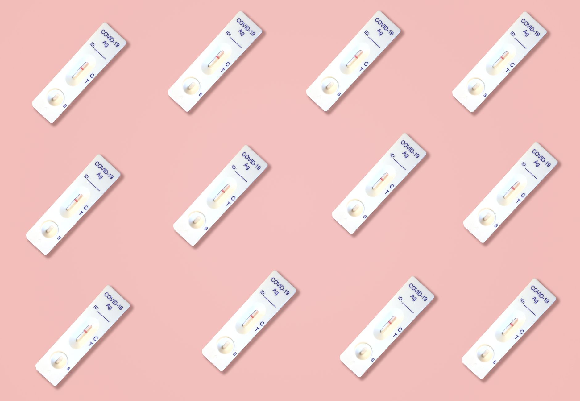Multiple Covid-19 antigen test kits arranged on a pink surface, ideal for health-related content.